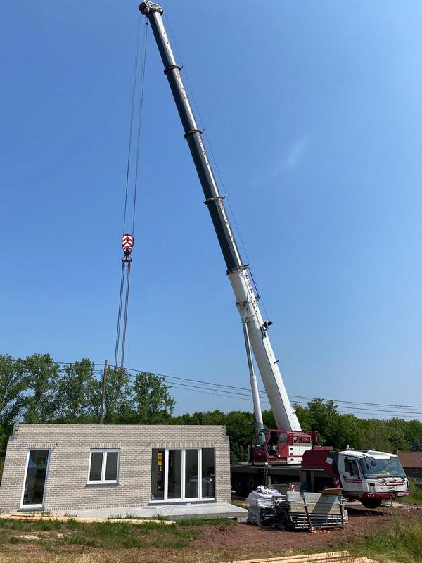 L'entreprise utilise trois grues qui sont utilisées pour assembler des maisons préfabriquées