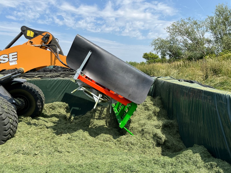 Une fourche d’ensilage repliable hydrauliquement est utilisée pour placer l’ensilage au bout des silos couloirs.
