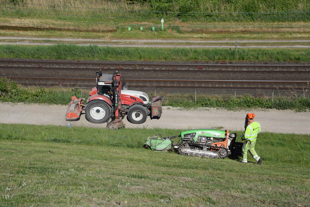L'opérateur reste toujours au-dessus de sa machine. En bas, on aperçoit une combinaison avec un broyeur à bras.